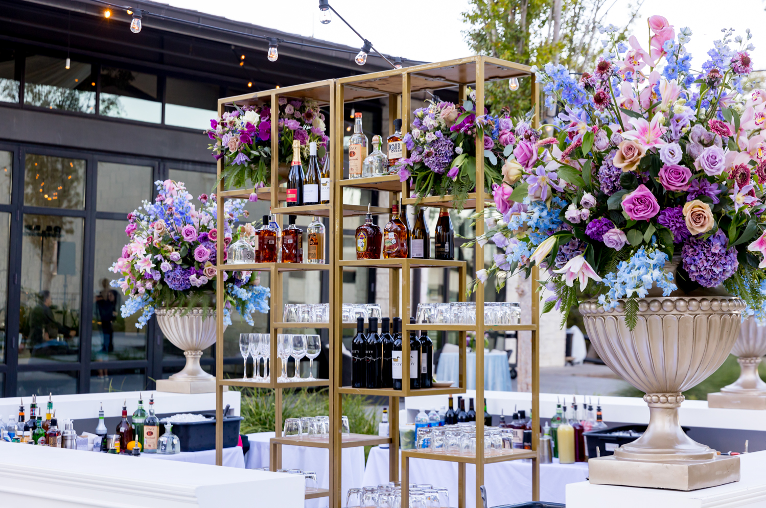 A close-up shot of the outdoor bar and large blue, purple, and pink flower arrangements