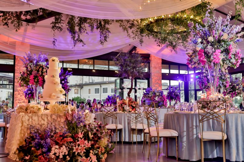 Wedding reception inside the Pavilion at Omni Barton Creek with hanging floral installations and colorful lighting