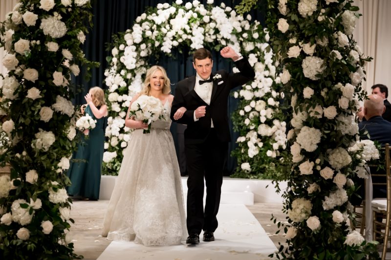Bride standing beneath white and green floral arches during her Four Seasons Austin ceremony