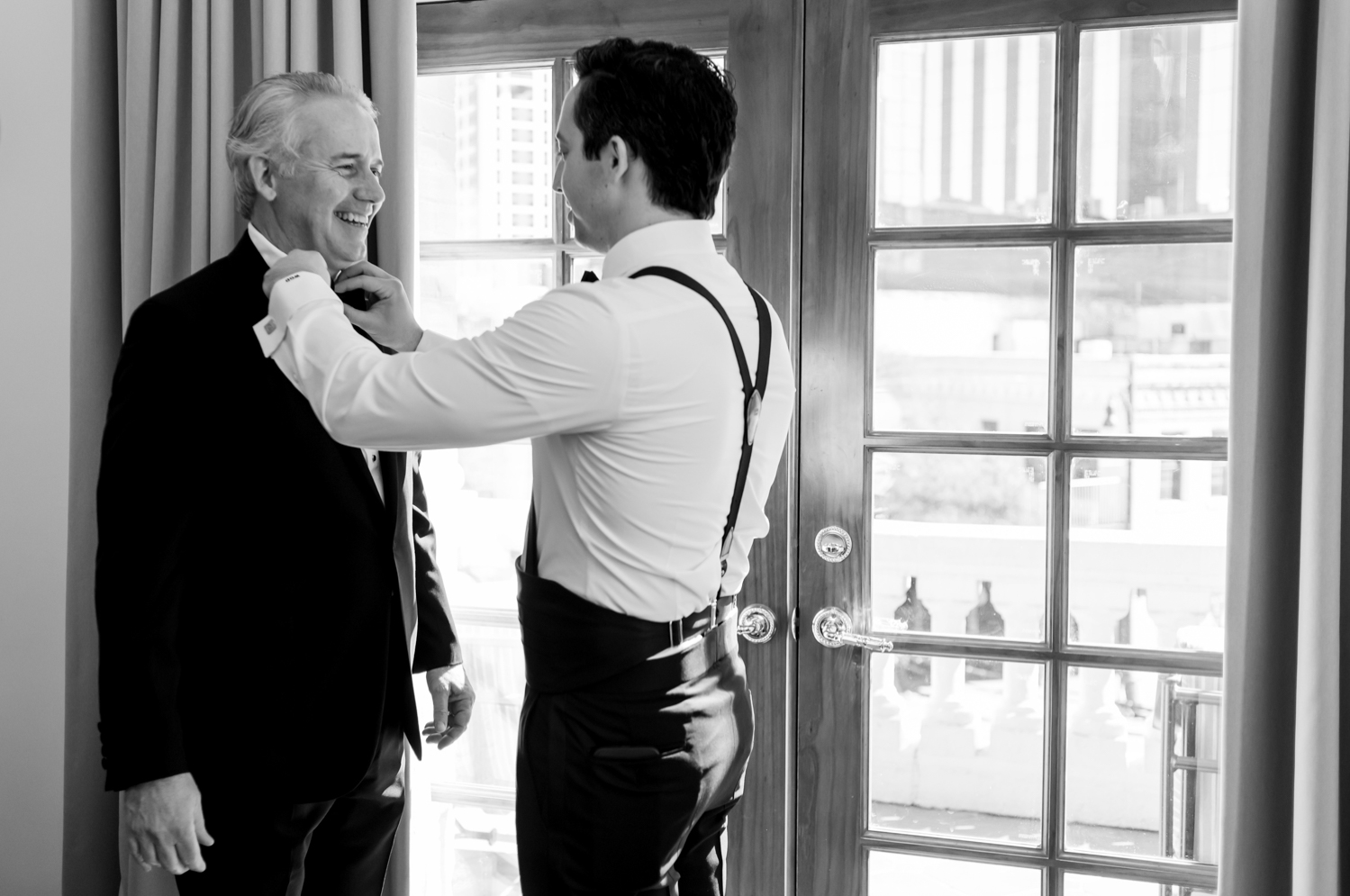 The groom adjusts his father's bow tie before the wedding