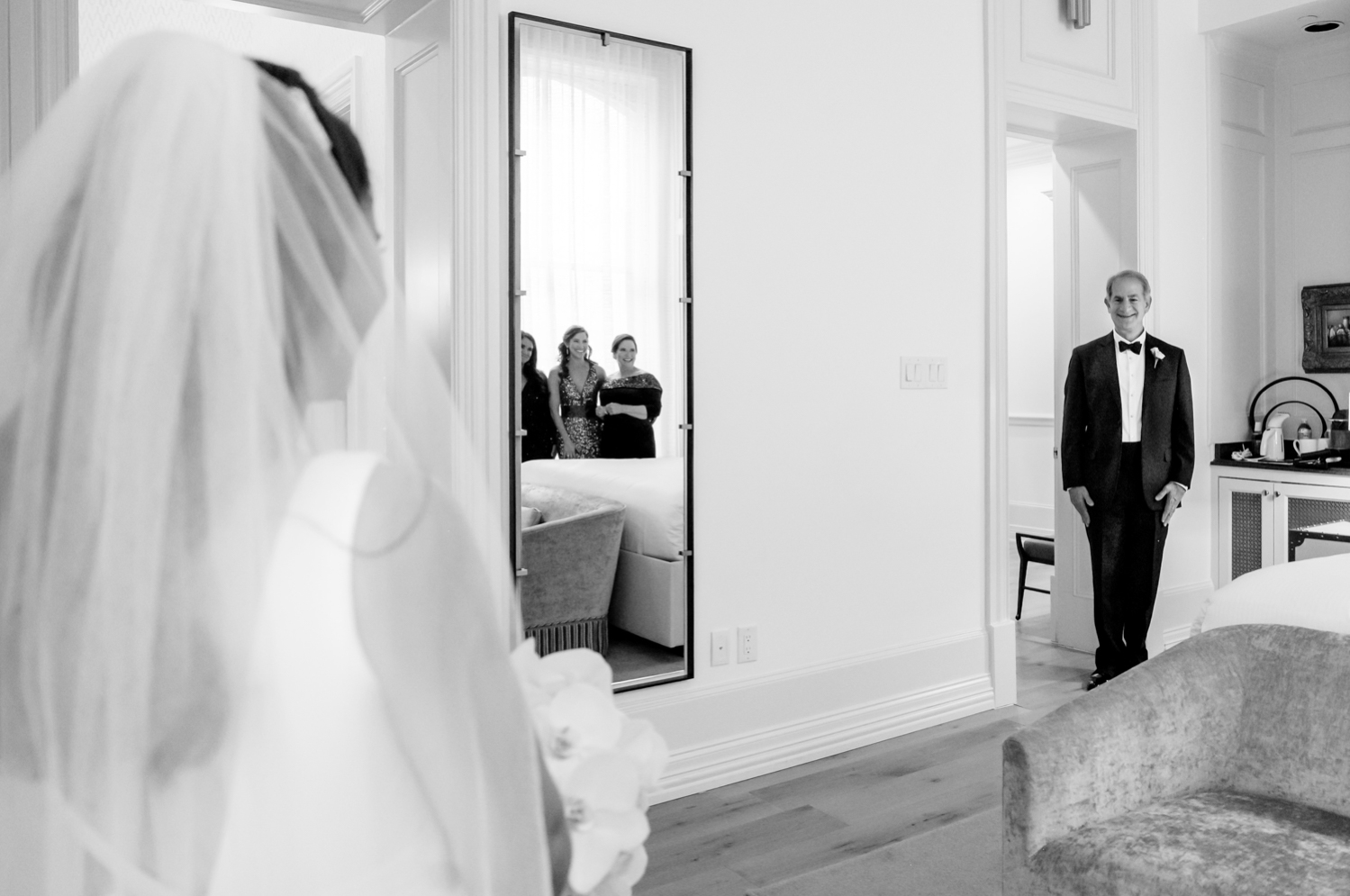 The father of the bride smiles as he sees his daughter in her wedding dress for the first time.