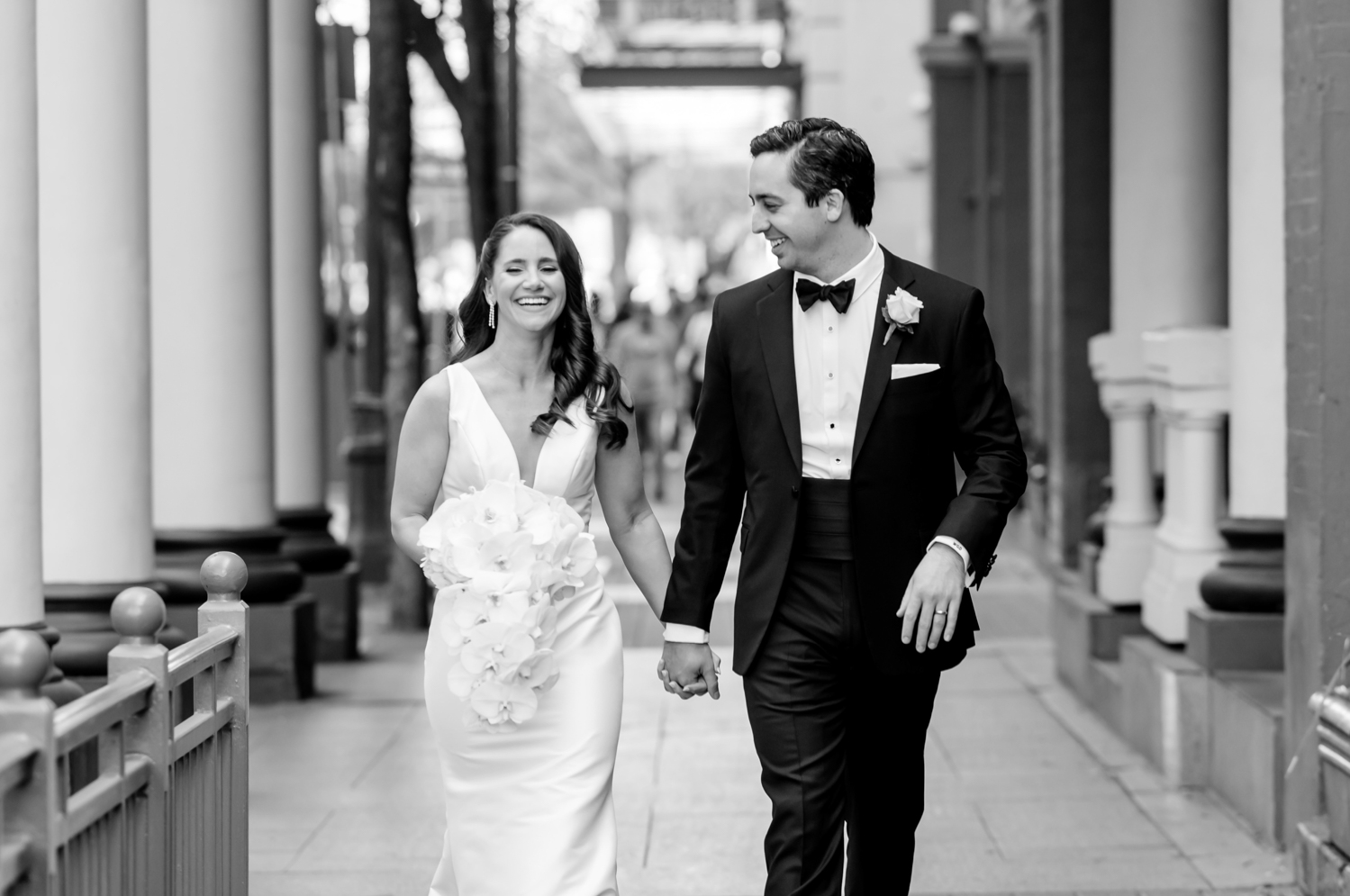 The bride and groom hold hands and laugh as they walk together in the streets of Austin, Texas.
