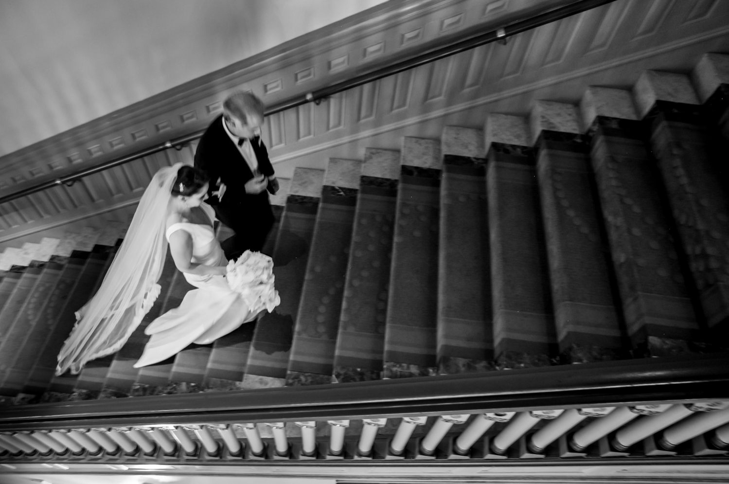 An aerial shot of the bride walking up the stairs to the ceremony, arm-in-arm with her father.