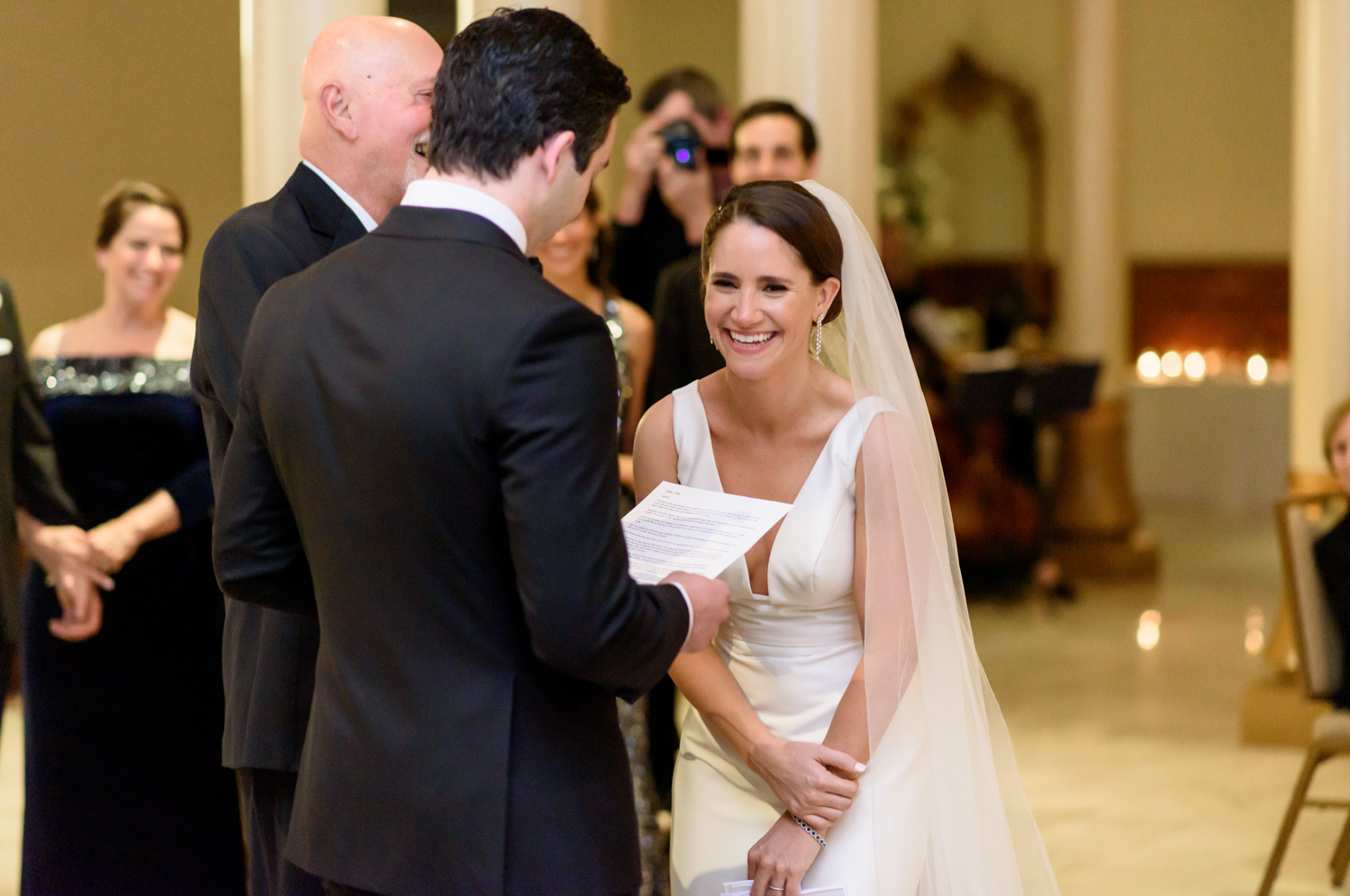 The bride laughs as the groom reads his vows