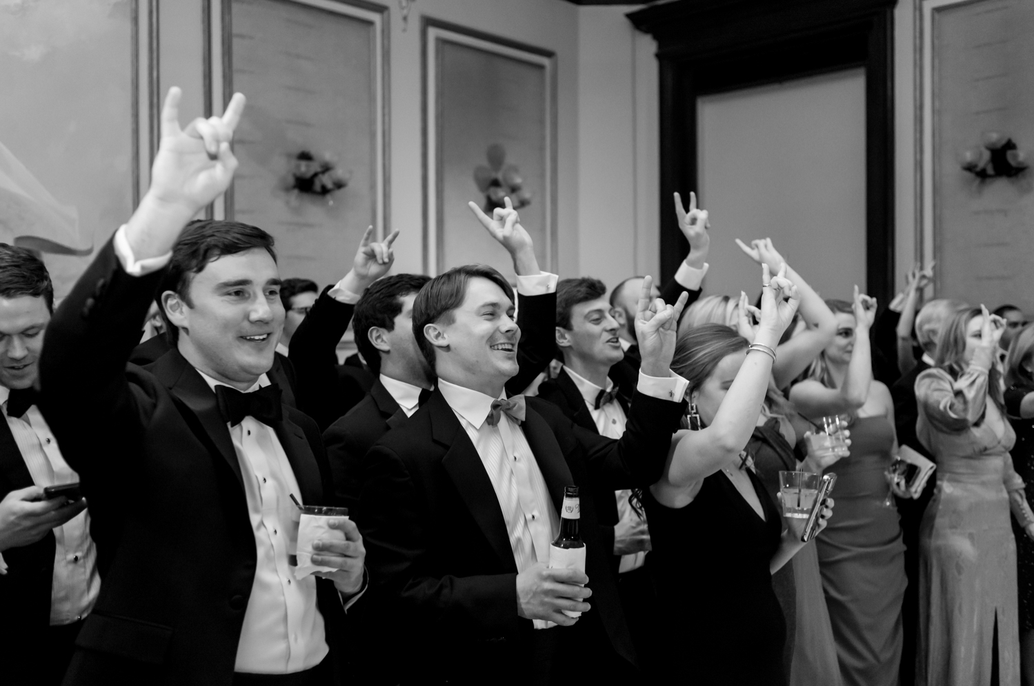 The crowd watches the bride dance with her father as they all hold up the "hook em" hand sign from The University of Texas at Austin.