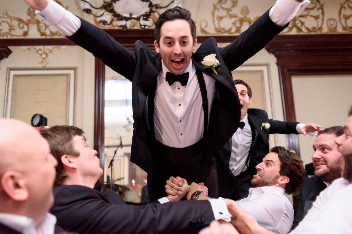 The groom leaps into the crowd with his arms outstretched like Superman.