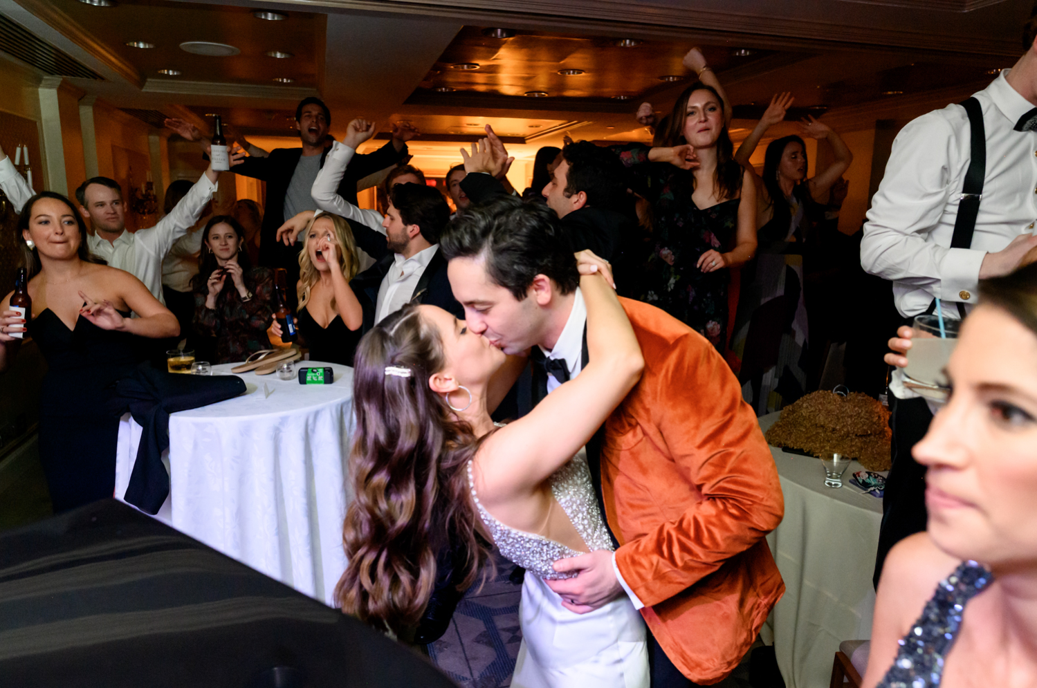 The bride and groom kiss as their guests at the after party cheer.