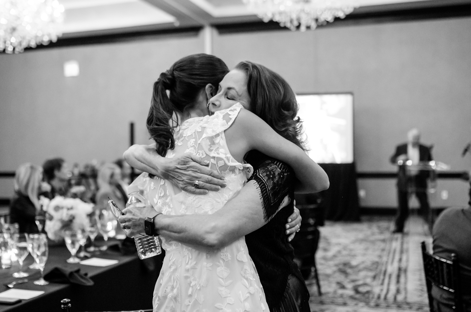 The bride hugs her mother at the rehearsal dinner