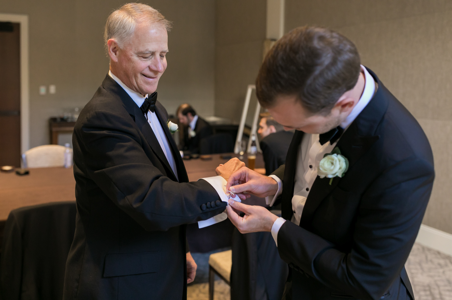 The groom pins a cufflink on his father