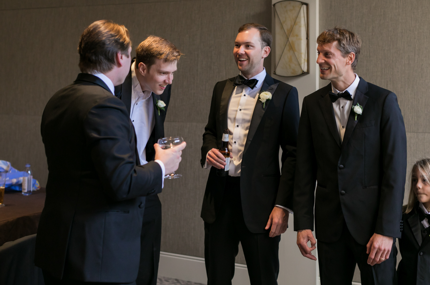 The groom laughs with his groomsmen as they share drinks before the ceremony