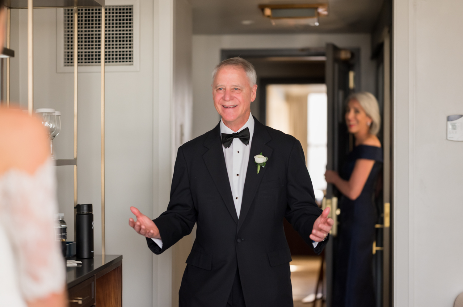 The father of the bride smiles as he sees his daughter in her wedding dress for the first time