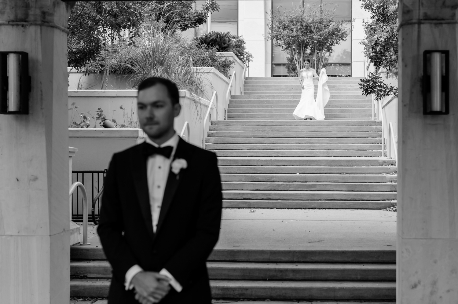 The bride walks down the stairs at the Four Seasons where her groom is waiting to see her for the first time