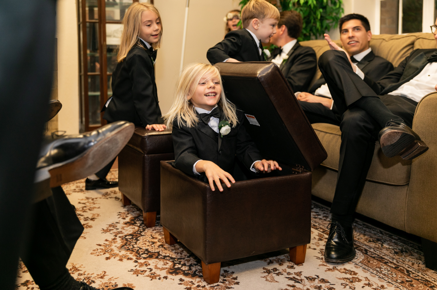 Kids play around with the groomsmen and hide in the ottomans.