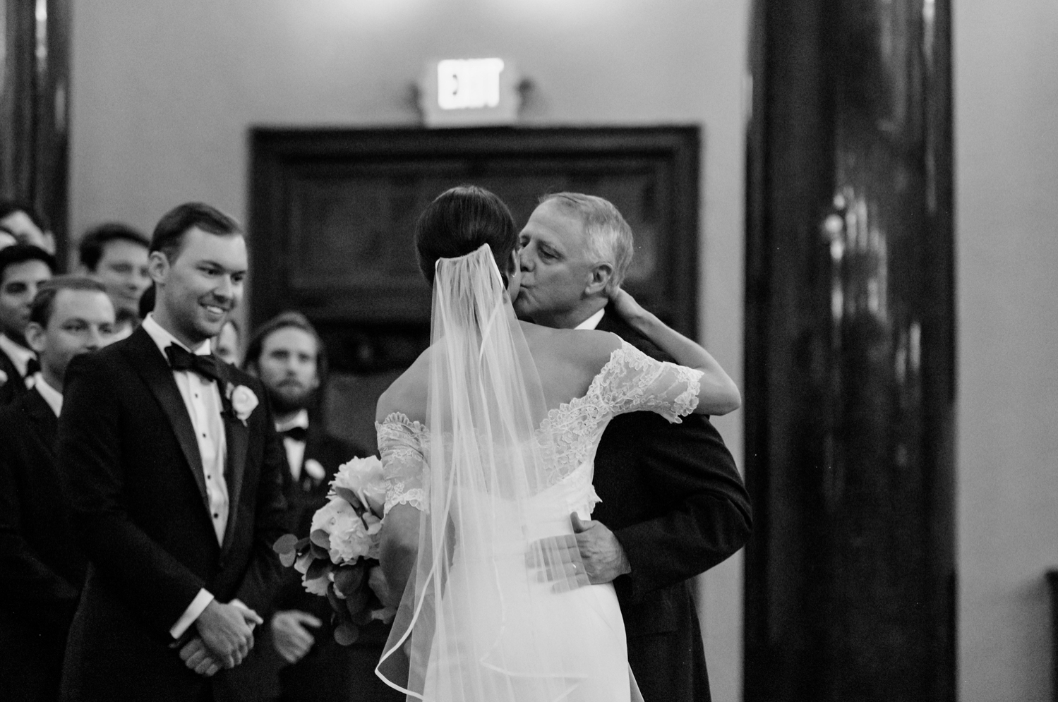 The father of the bride kisses her on the cheek before parting ways at the altar.