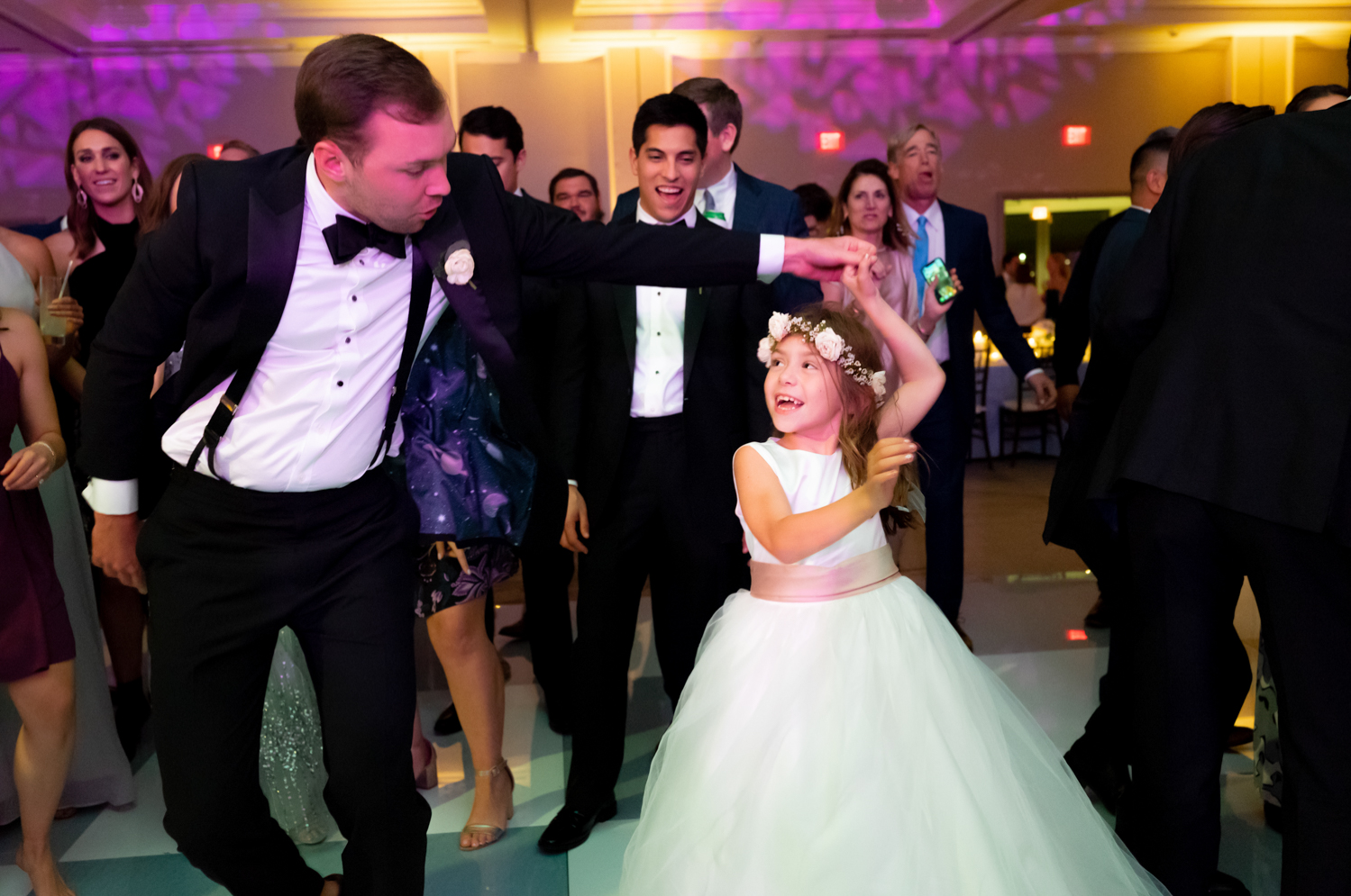 The groom spins the flower girl on the dance floor.