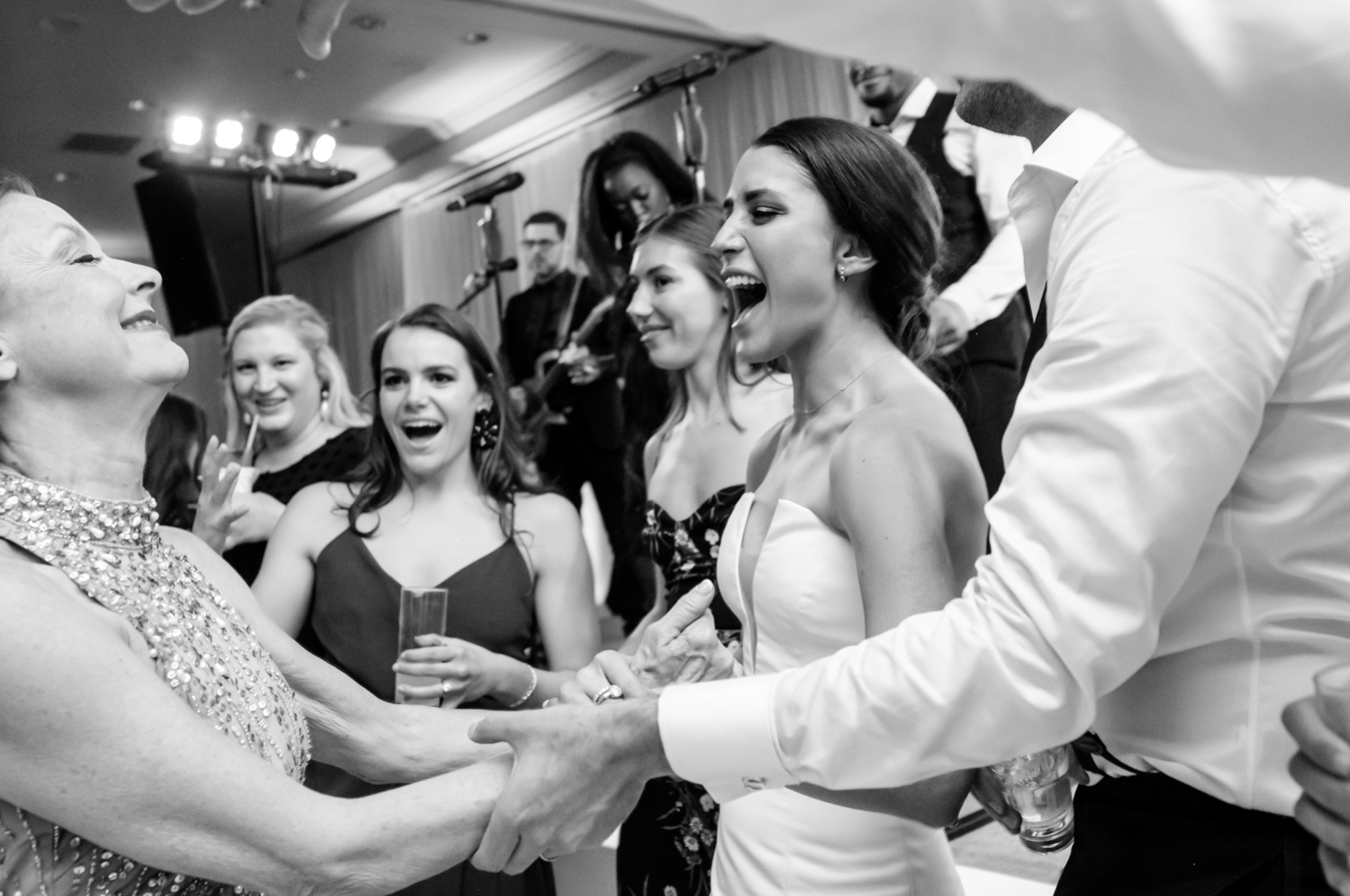The bride laughs as she dances with family.
