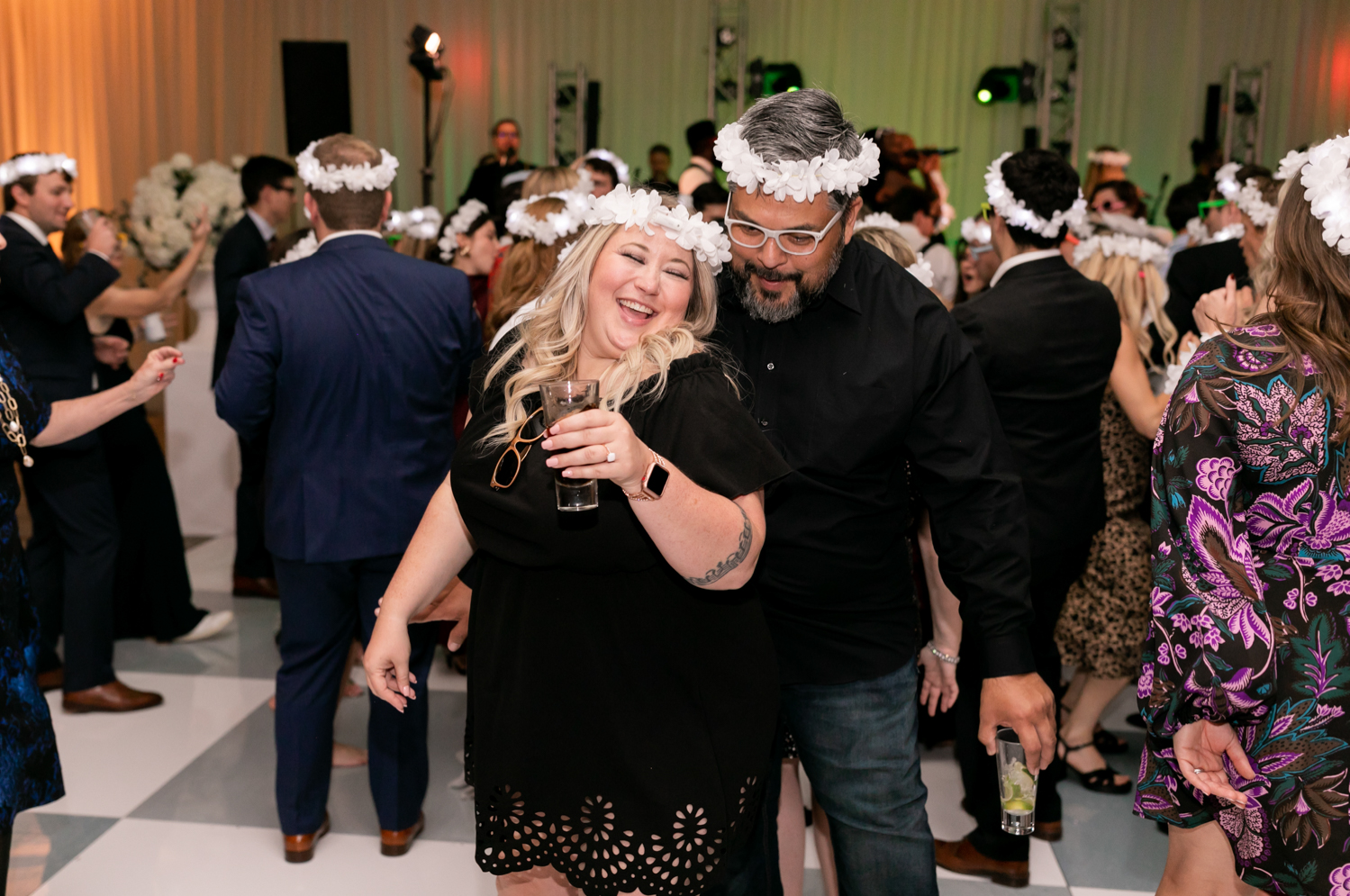 The couple dances on the floor, wearing white flower crowns along with the rest of the guests.