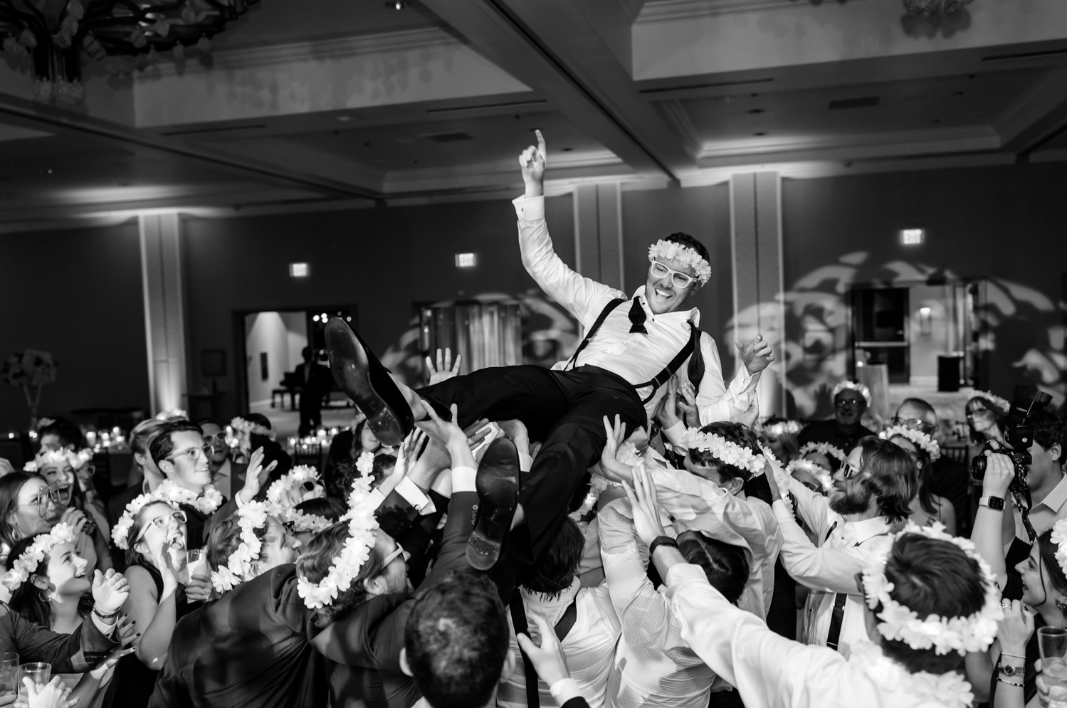 The groom crowdsurfs, hands in the air.