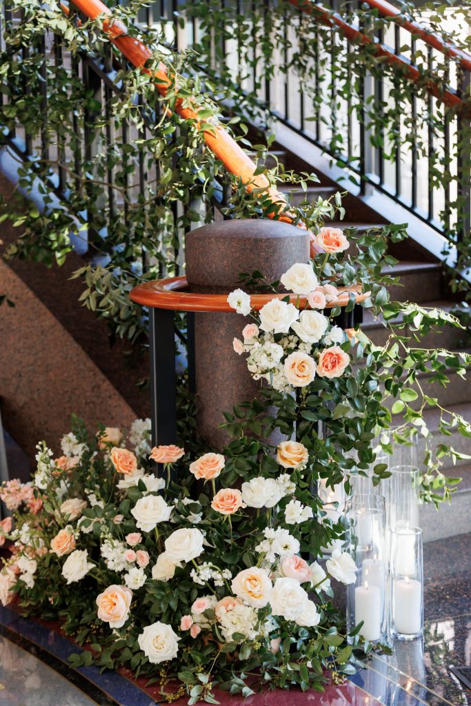 pastel pink and orange roses lining a staircase with greenery
