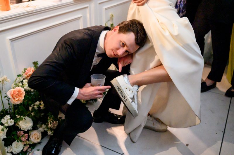 groom pointing to bride's reception shoes that have her new last name on them