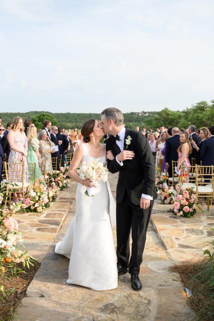 bride and groom kissing as they walk back down the aisle