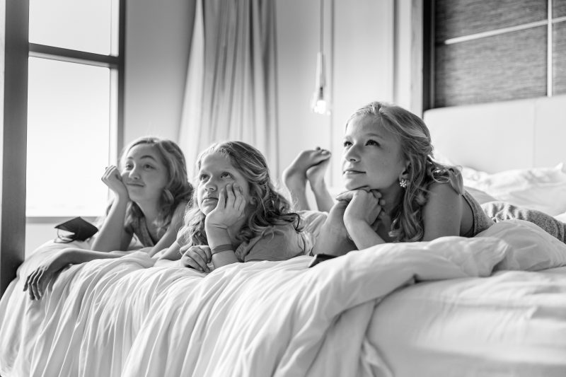 girls laying on the bed watching the bride get ready