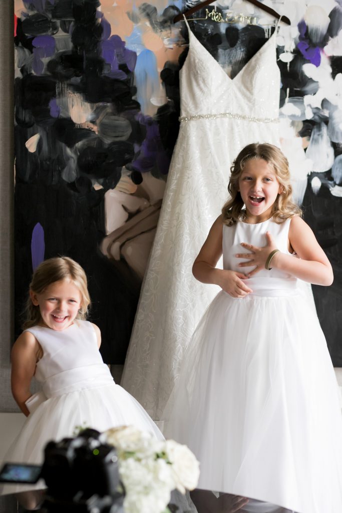 flower girls getting ready with the bride's dress in the background