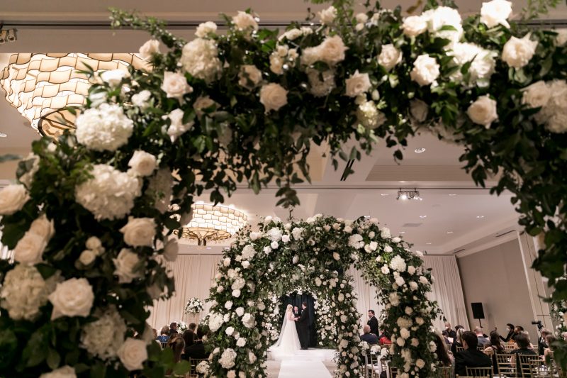 white floral archways with greenery lining the aisle
