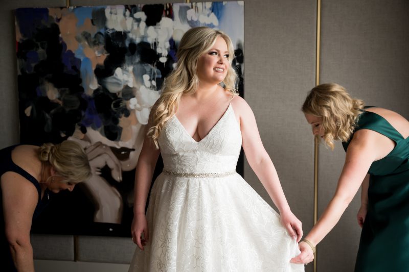 bride getting ready with he help of her bridesmaids