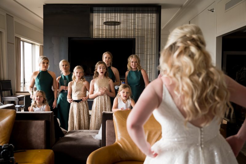 bride showing her bridesmaids her wedding dress