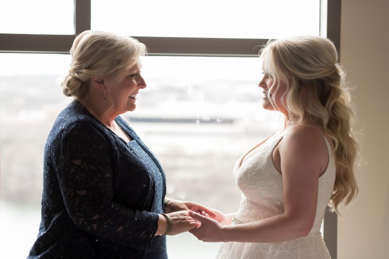 mother of the bride holding brides hands while she is getting ready