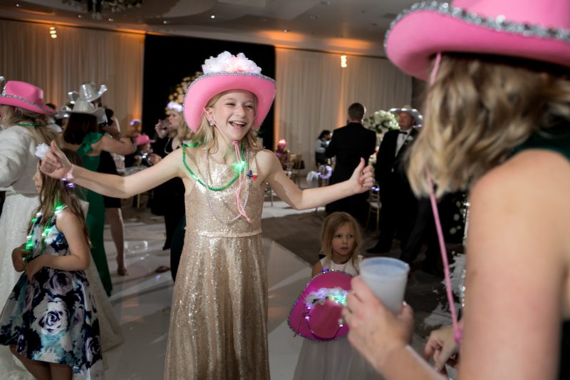 wedding guests dancing at the reception with pink cowboy hats