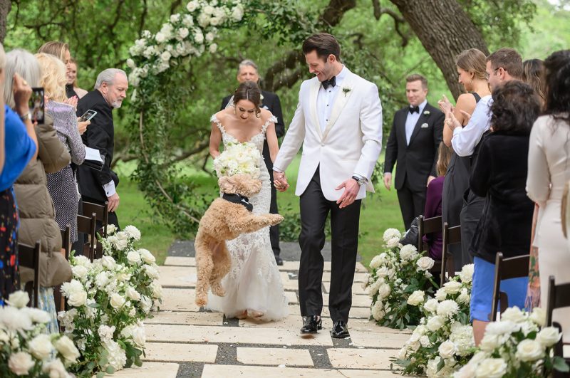 bride and groom walking back down the aisle with their puppy