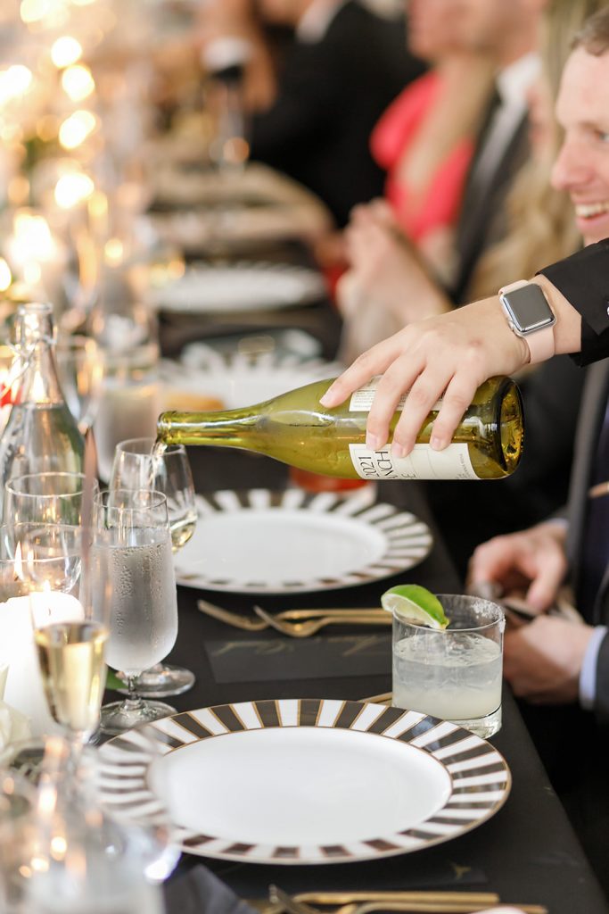 waitress pouring white wine into guests glasses