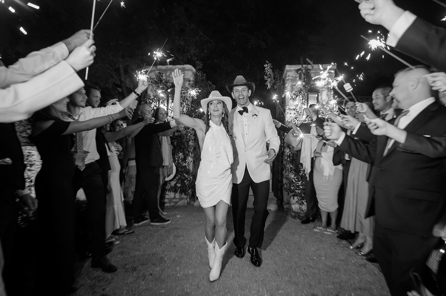 bride and groom exiting the reception with guest standing by holding sparklers