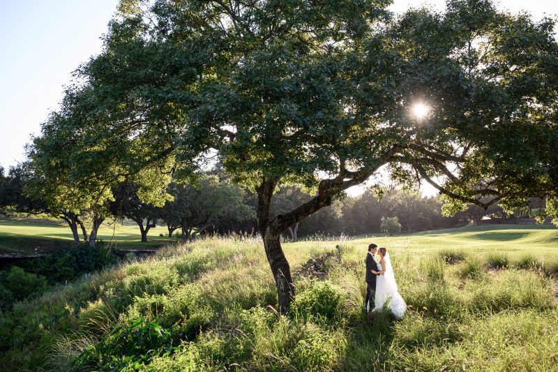 Bride and groom walking near sunset along the Fazio Canyons golf course at Omni Barton Creek just before the bridge over the creek