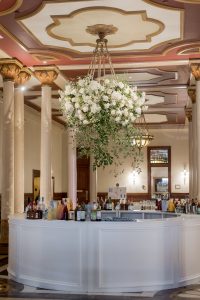 Wedding bar setup on The Driskill mezzanine beneath floral arrangements and chandeliers