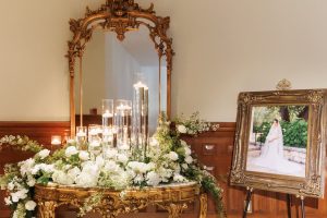 Wedding floral display and candles arranged beside a gilded mirror at The Driskill