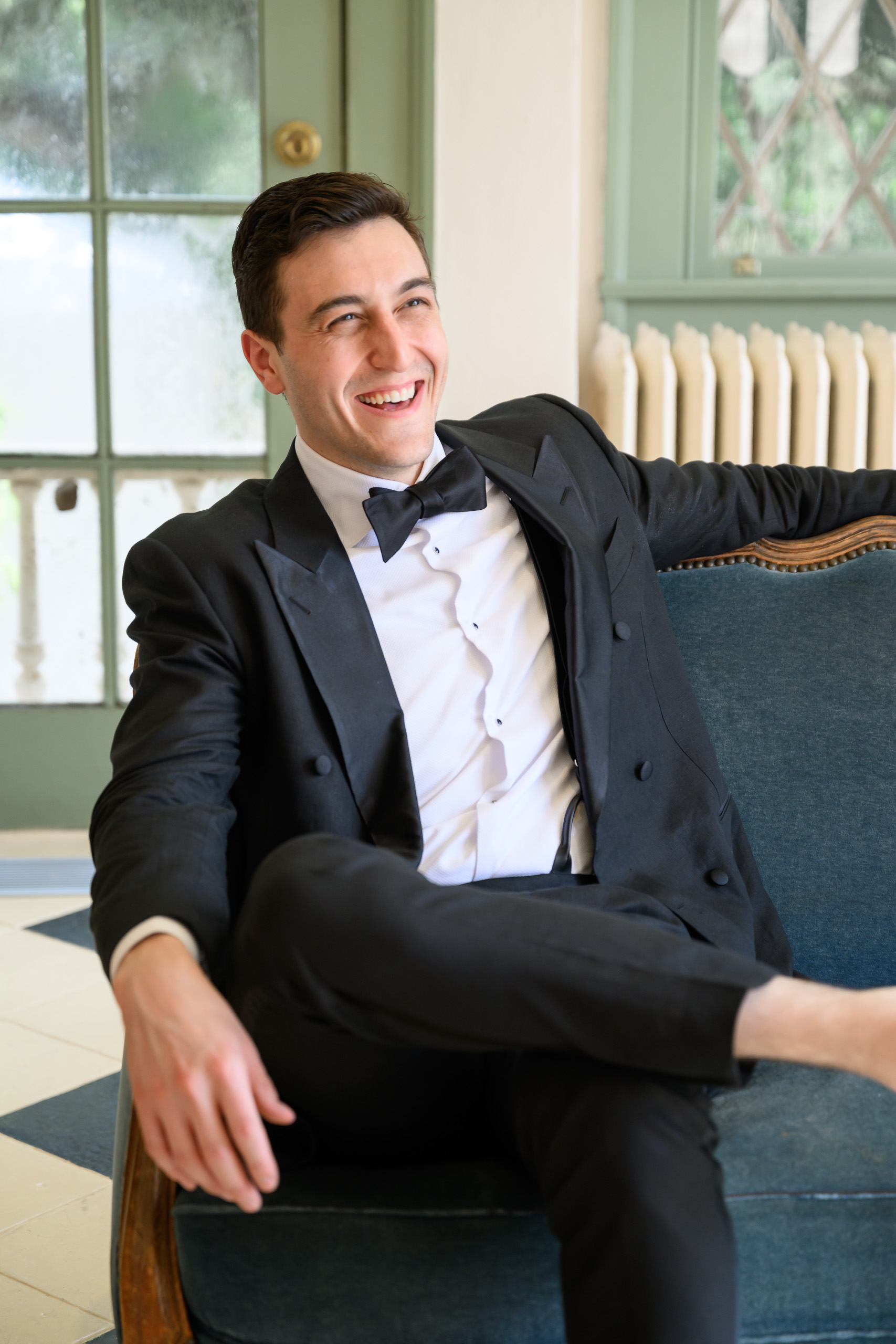 Groom in a tuxedo seated inside the historic Driscoll Villa at Laguna Gloria