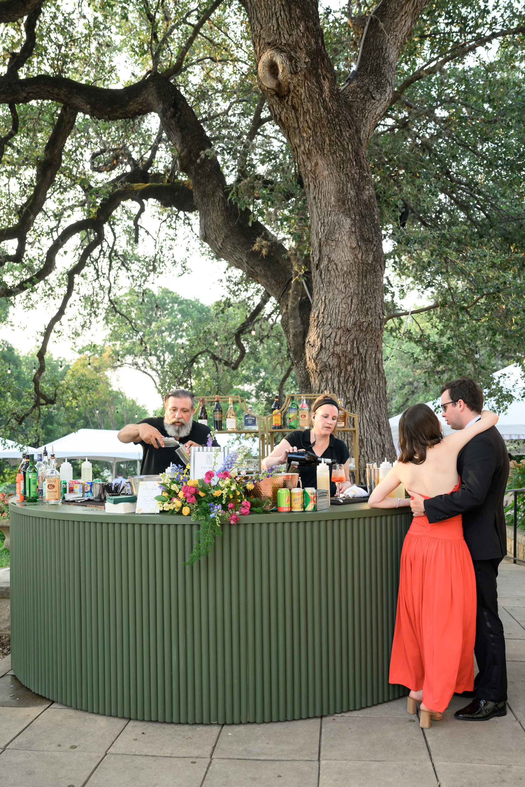 Guests gathering at an outdoor wedding bar beneath the oak trees at Laguna Gloria