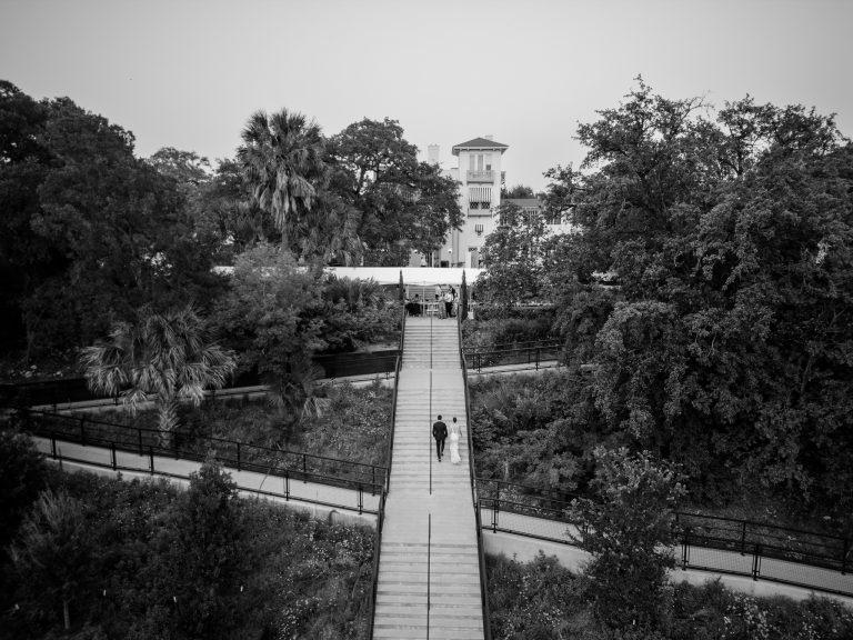 bride and groom walking up the long staircase with the Laguna Gloria building at the top of the hill