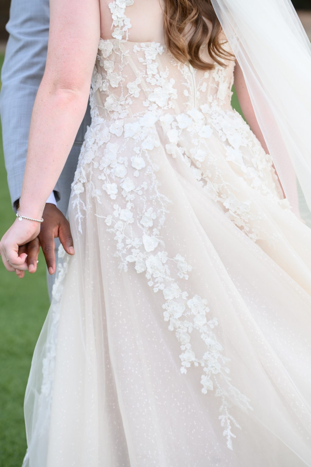 A close-up of Kelli’s wedding dress, highlighting the intricate lace detailing and flowing fabric, emphasizing timeless bridal style.