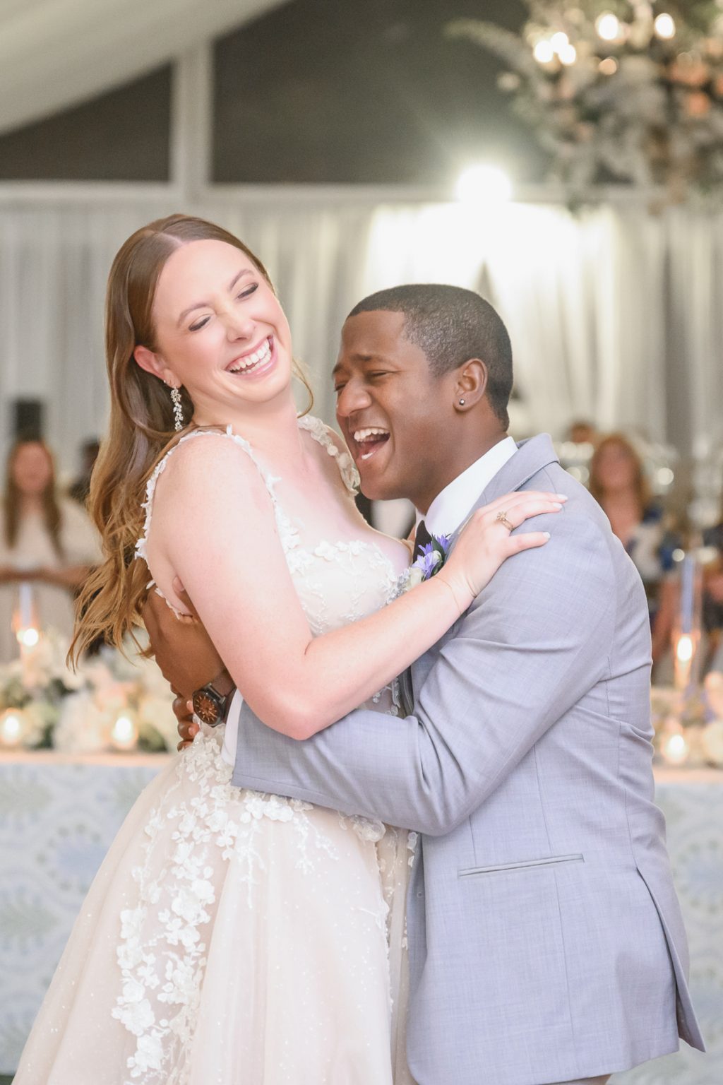 Kelli and Reggie sharing an emotional first dance, surrounded by twinkling lights and the warmth of their wedding guests.