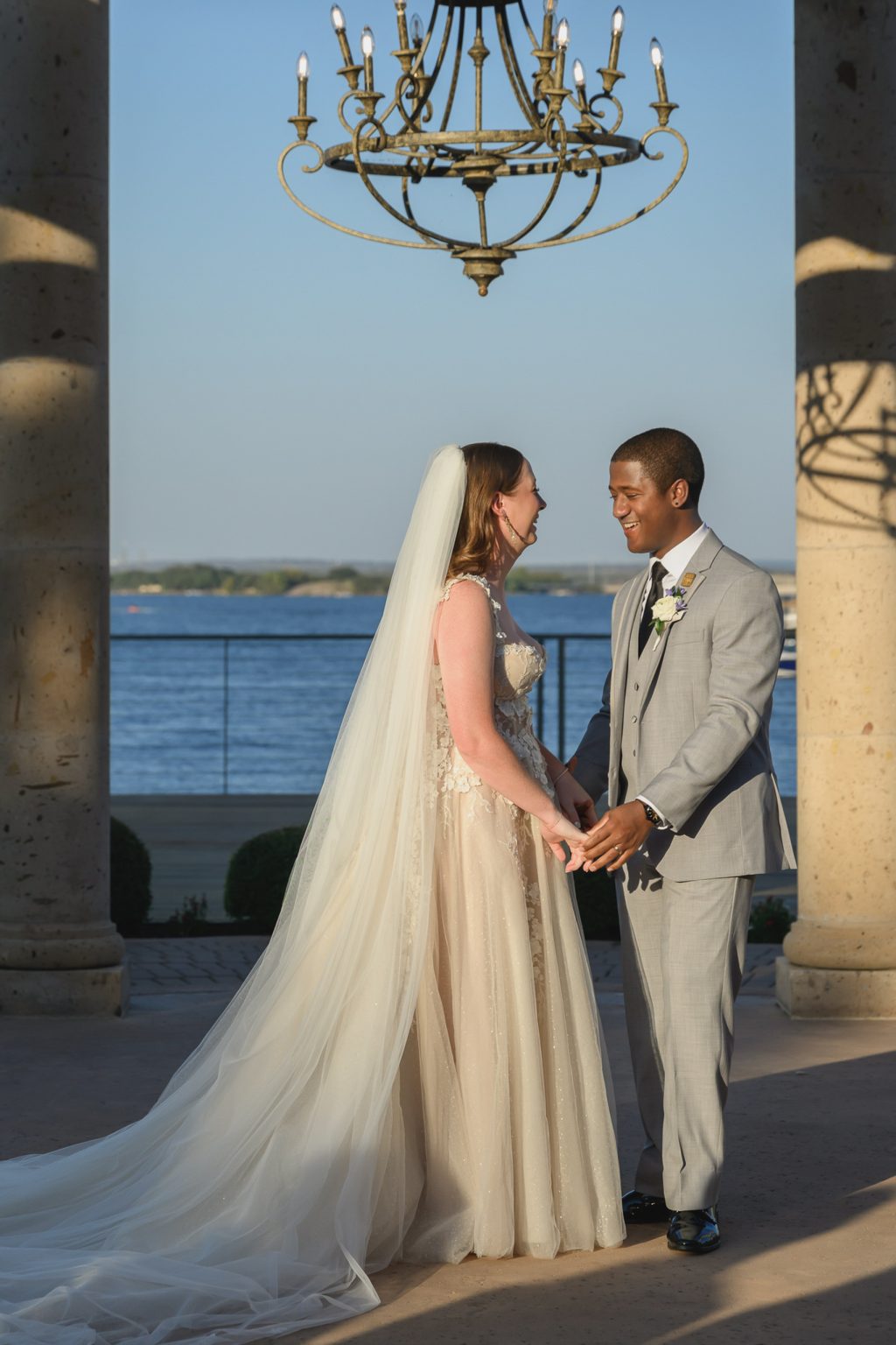 Kelli and Reggie standing beneath a grand chandelier, framed by the soft glow of sunset filtering through the reception tent at Horseshoe Bay Resort.