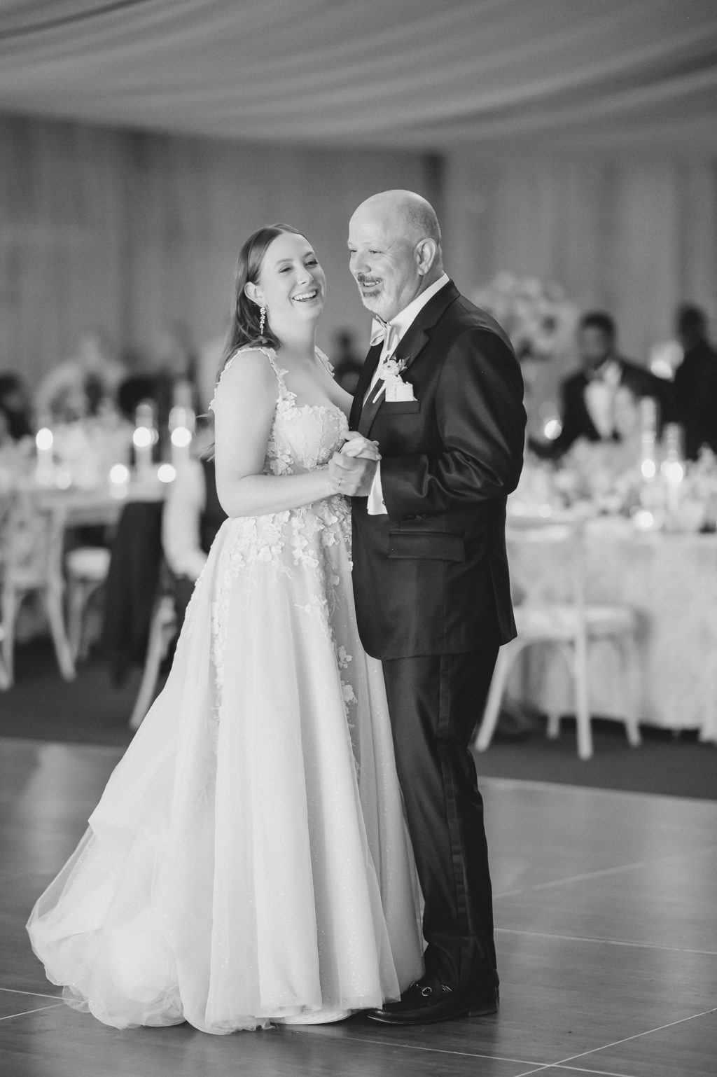A classic black-and-white image of the bride dancing with her father under the warm glow of the Horseshoe Bay Resort reception tent, capturing a timeless emotional moment.