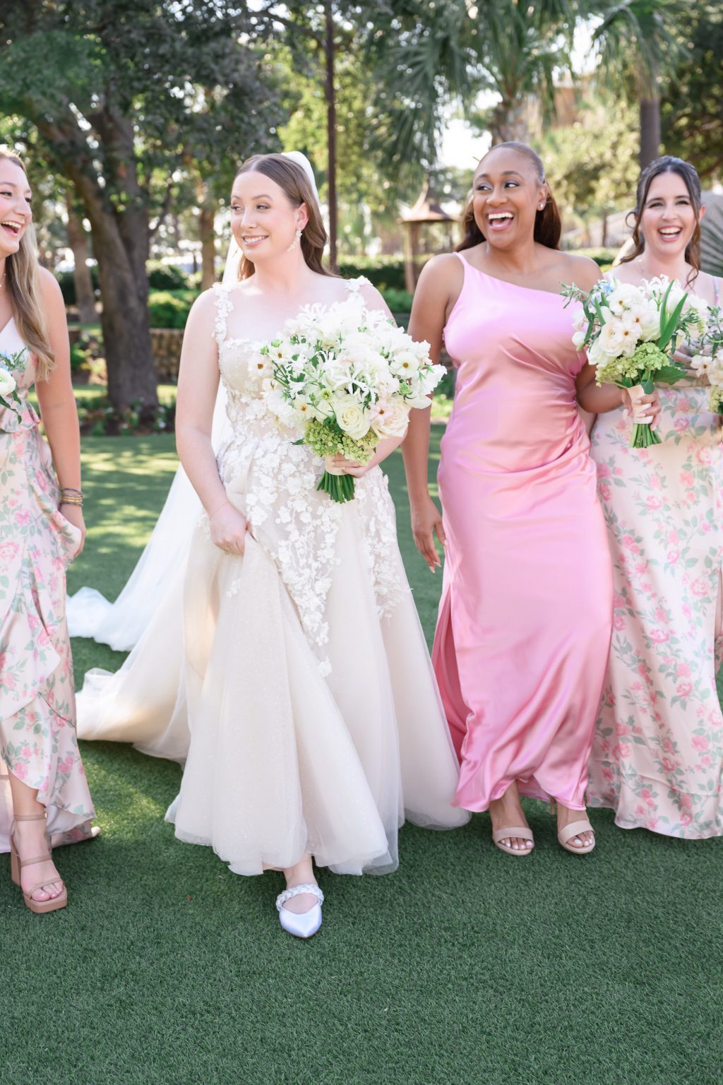 The bride with her bridesmaids in soft blush and floral gowns, standing on the manicured lawn of Horseshoe Bay Resort, bathed in warm afternoon light.