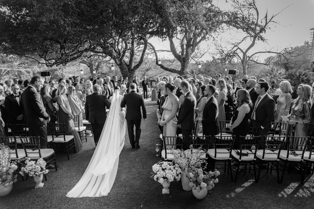 Black and white photograph of a wedding ceremony beneath the trees on the Four Seasons Austin Lawn