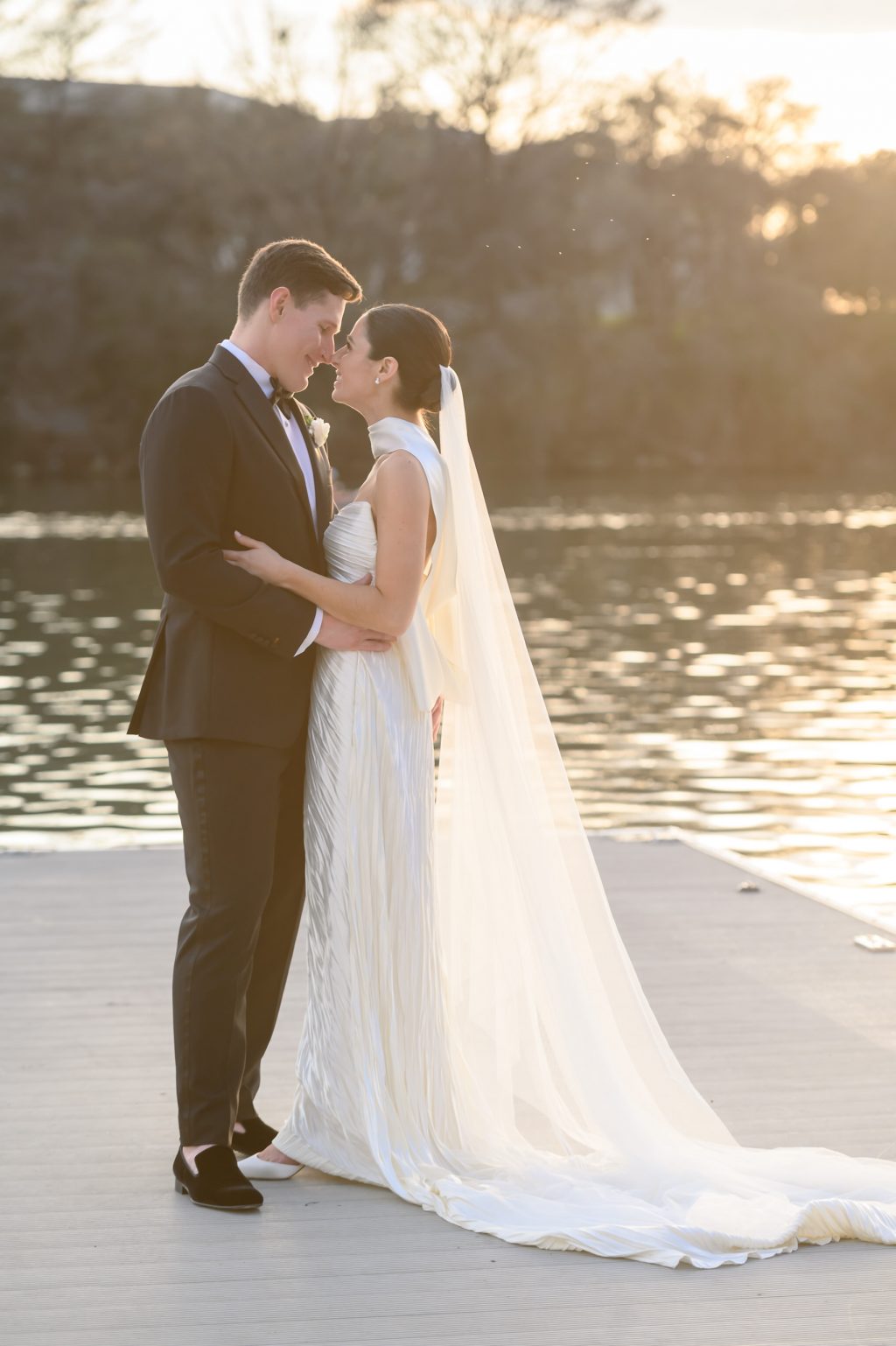Bride and groom embracing in warm sunset light beside Lady Bird Lake