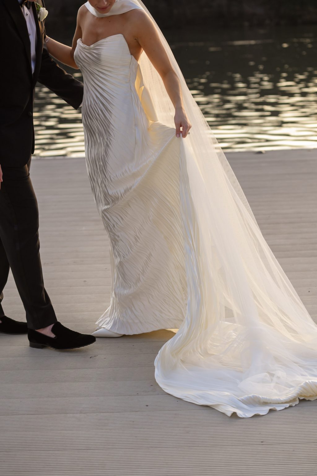 Close view of a bride’s wedding dress moving along the dock at Four Seasons Austin