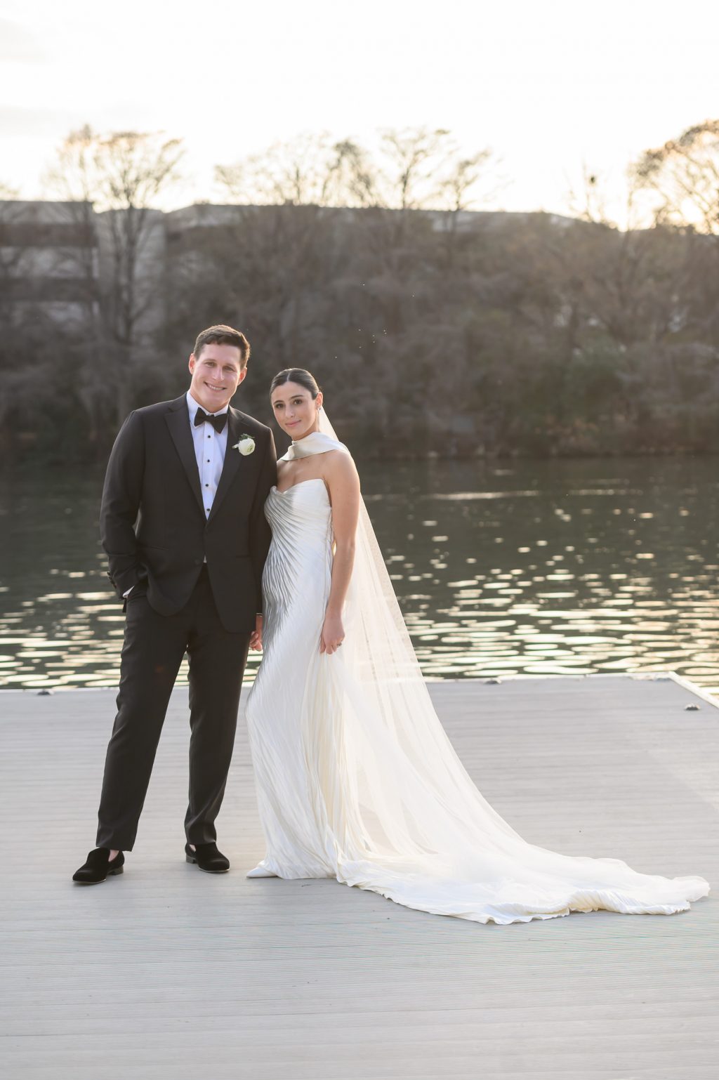 Bride and groom standing on the dock beside Lady Bird Lake at Four Seasons Austin